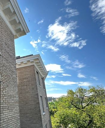 a view of a brick building and a blue sky with clouds